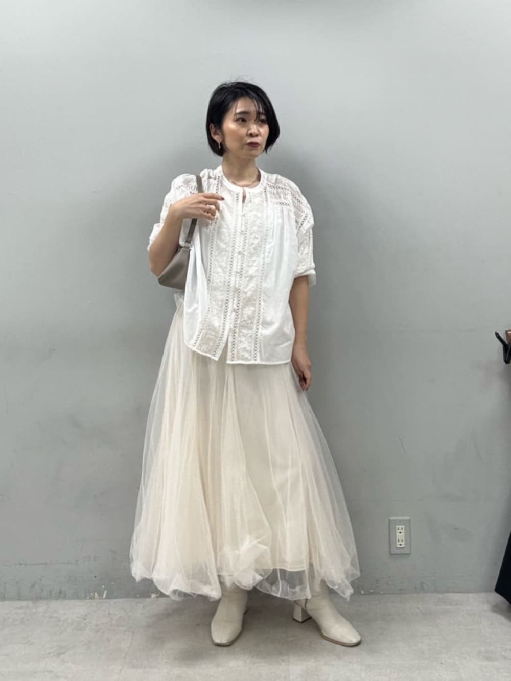 ホワイト系のスカート、ベージュ系のショルダーバッグを着用したレディースの春コーディネートの3枚目の写真