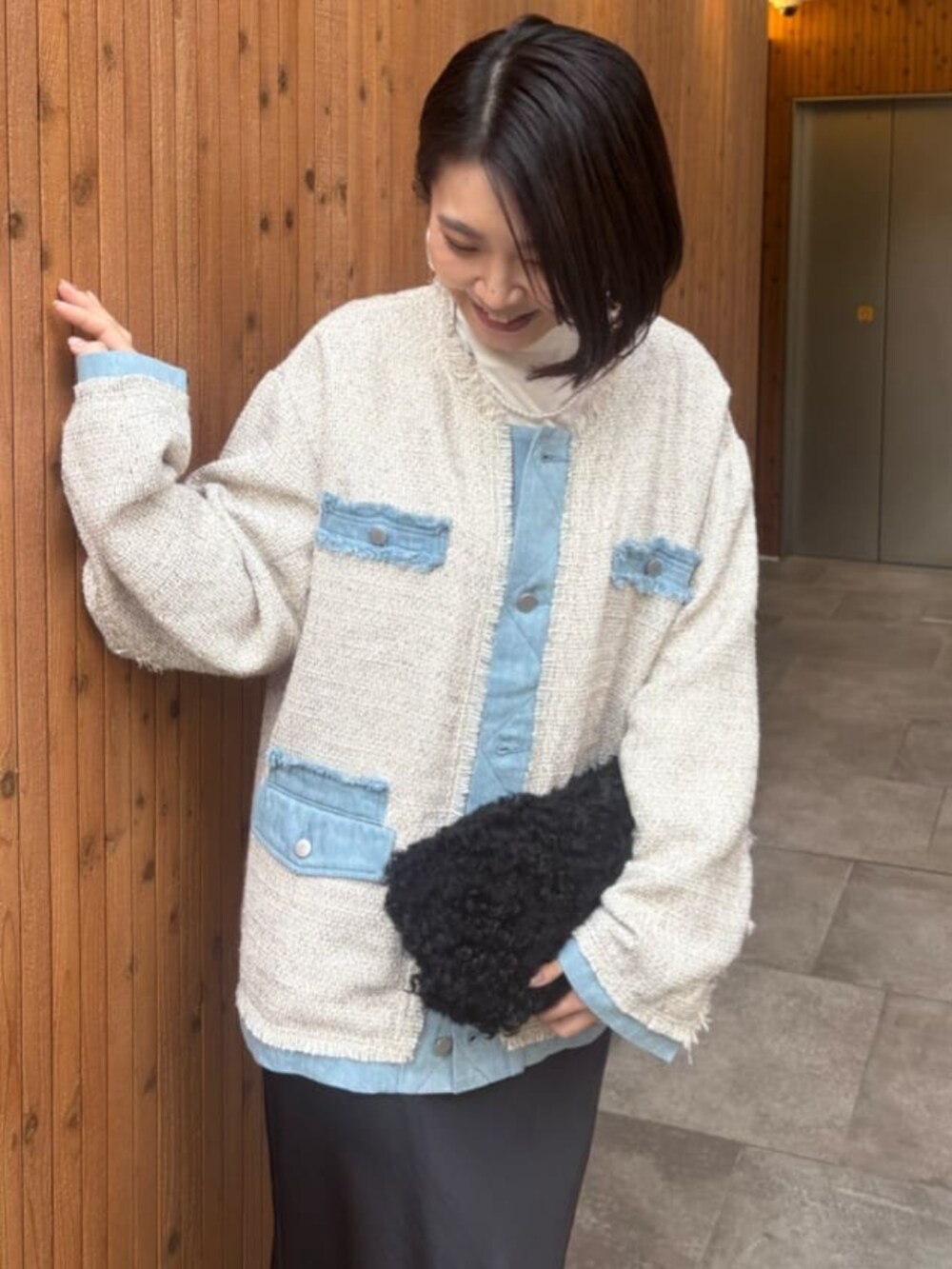 ブラック系のスカート、ホワイト系のノーカラージャケットを着用したレディースの冬コーディネートの2枚目の写真