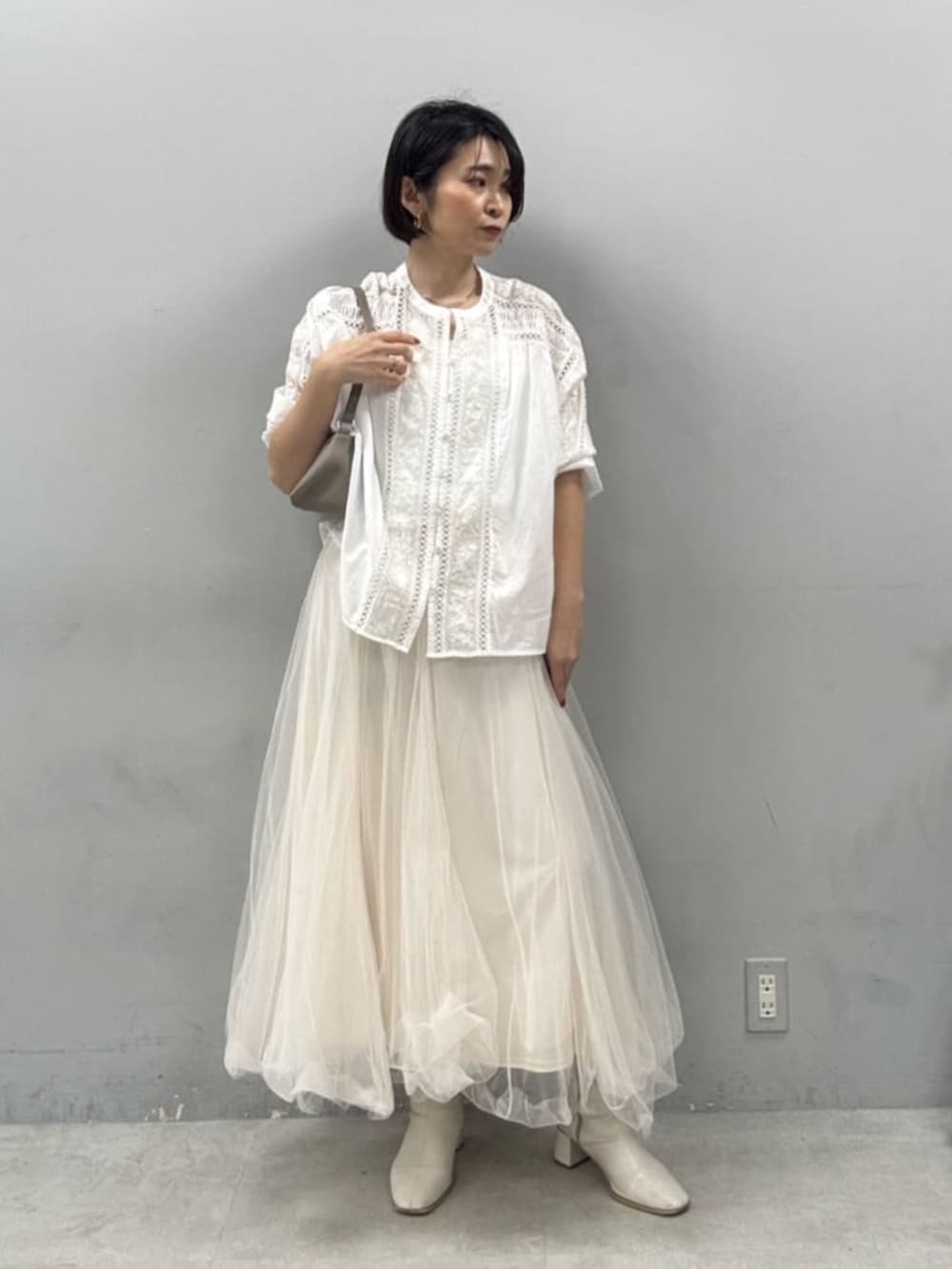 ホワイト系のスカート、ベージュ系のショルダーバッグを着用したレディースの春コーディネートの2枚目の写真