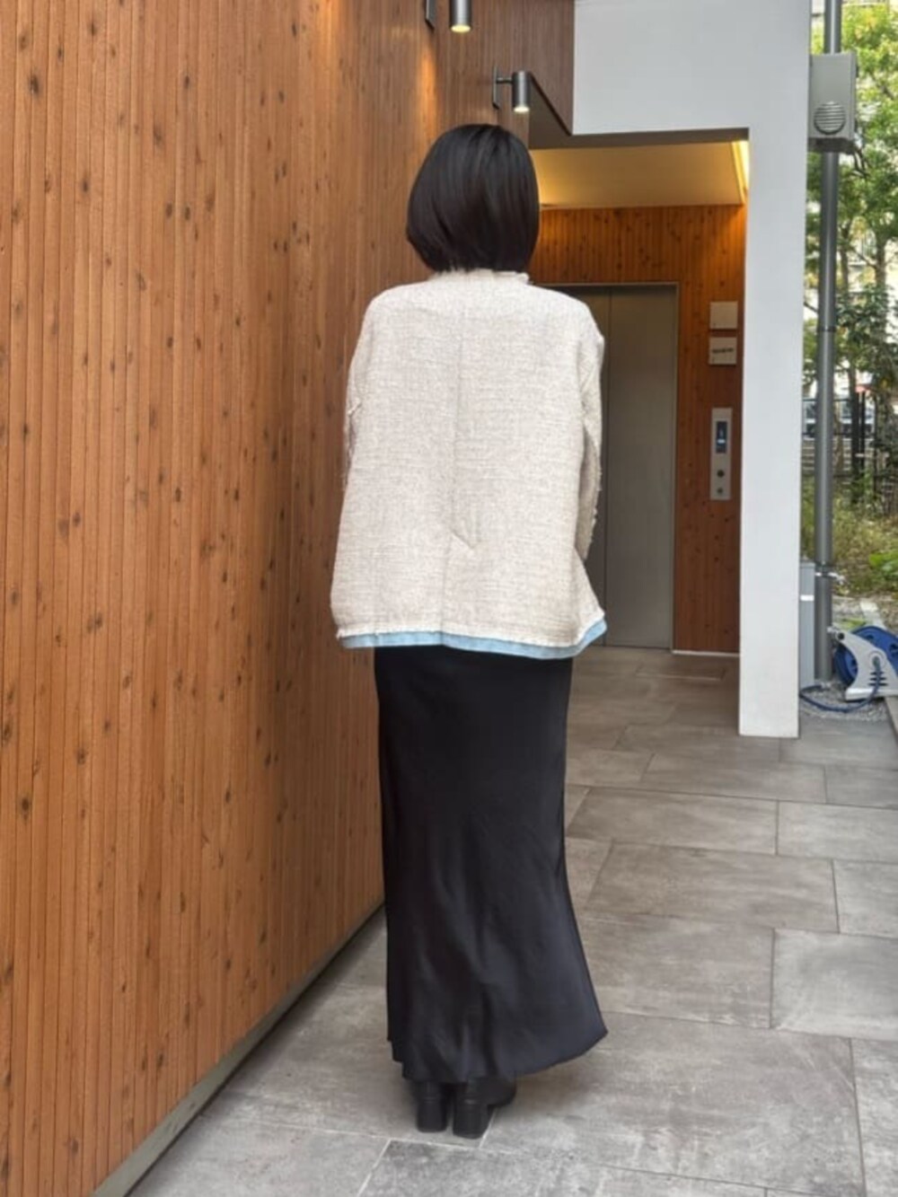 ブラック系のスカート、ホワイト系のノーカラージャケットを着用したレディースの冬コーディネートの3枚目の写真