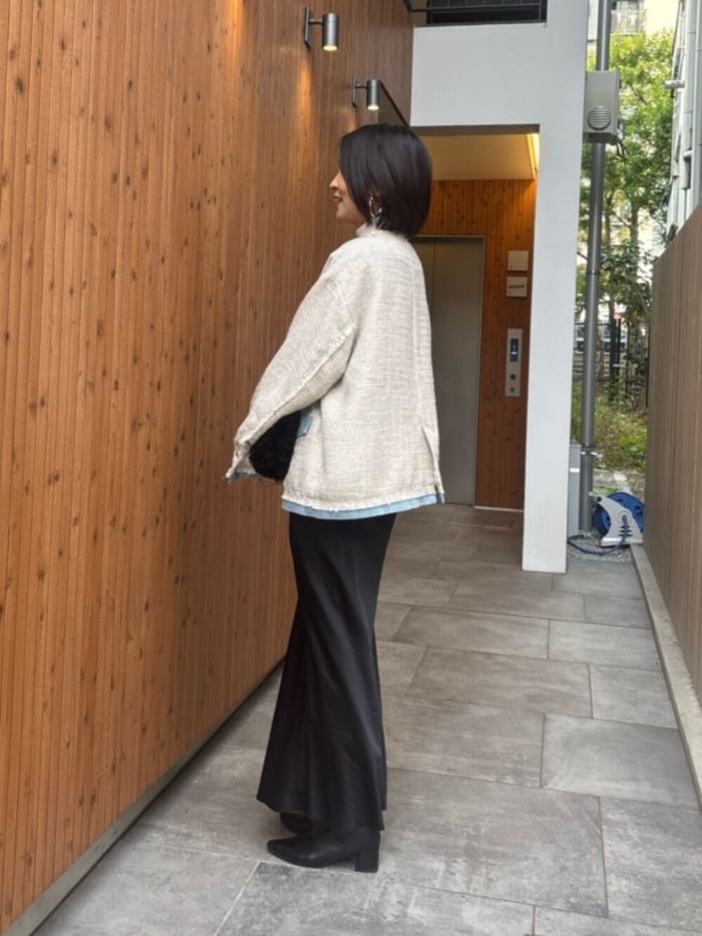 ブラック系のスカート、ホワイト系のノーカラージャケットを着用したレディースの冬コーディネートの4枚目の写真