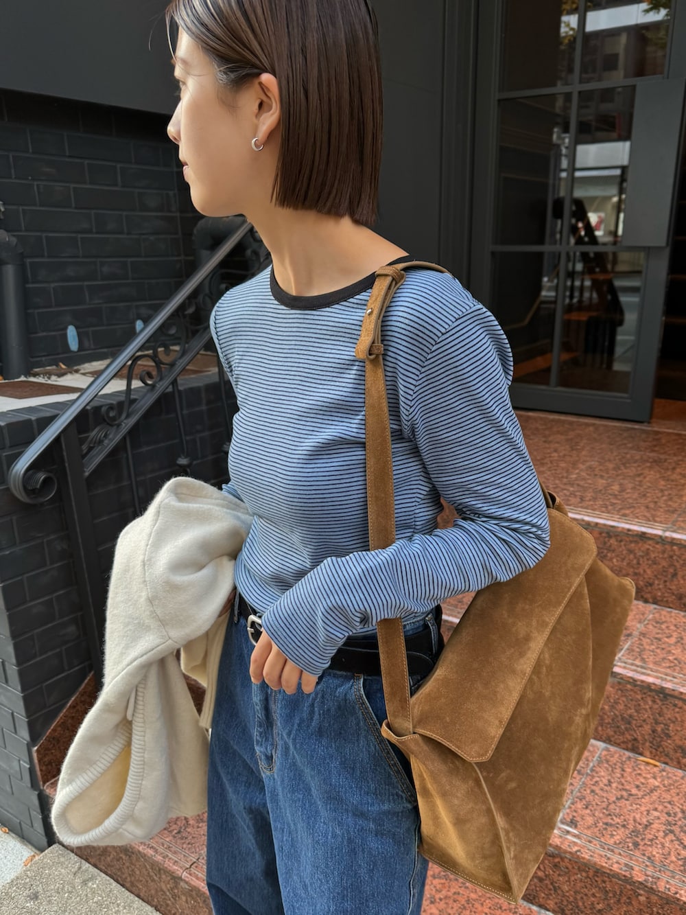 ホワイト系のニット/セーター、ブルー系のTシャツ/カットソー、イエロー系のショルダーバッグを着用したレディースの秋コーディネートの2枚目の写真