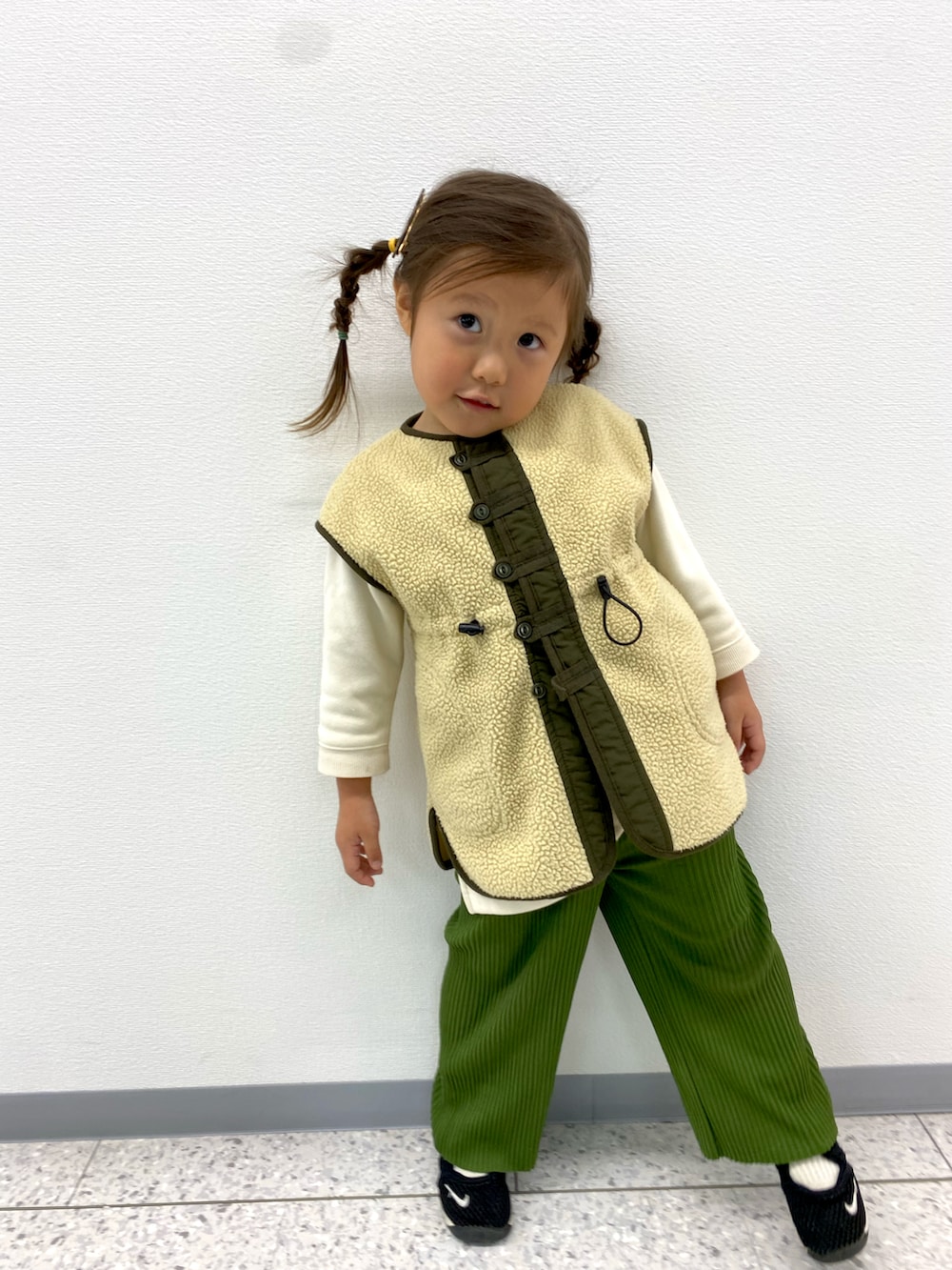 ベージュ系のベスト、グリーン系のその他パンツを着用したキッズの秋コーディネートの2枚目の写真