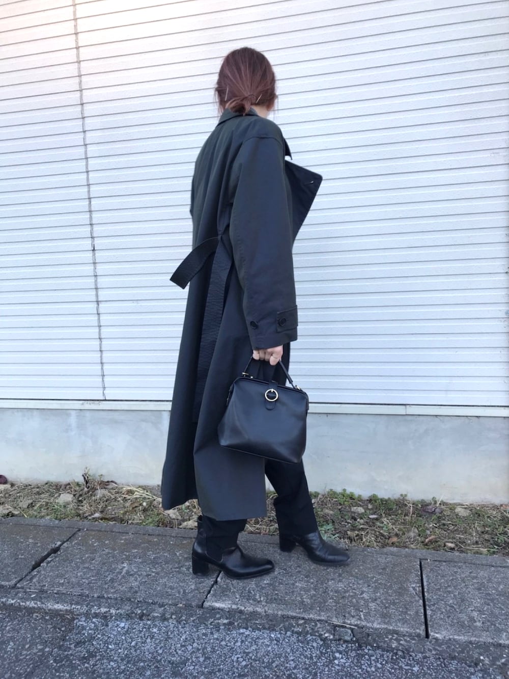 ブラック系のハンドバッグ、ブラック系のスラックス、ブラック系のトレンチコートを着用したレディースの秋コーディネートの2枚目の写真
