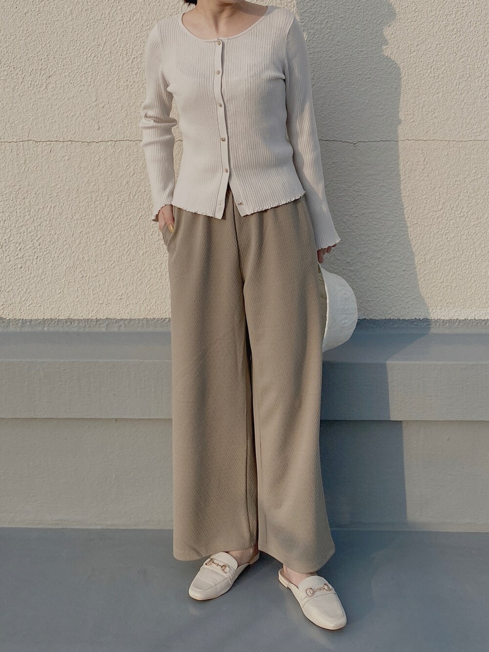 ホワイト系のサンダル、ブラウン系のその他パンツ、ホワイト系のカーディガン/ボレロを着用したレディースの冬コーディネートの2枚目の写真