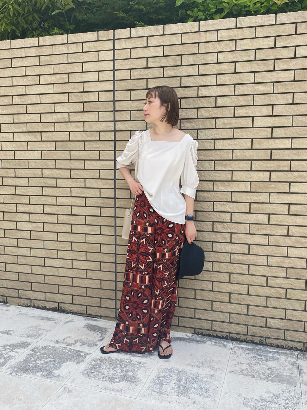 ブラウン系のパンツ、ブラック系のサンダル、ホワイト系のシャツ/ブラウスを着用したレディースの春コーディネートの2枚目の写真