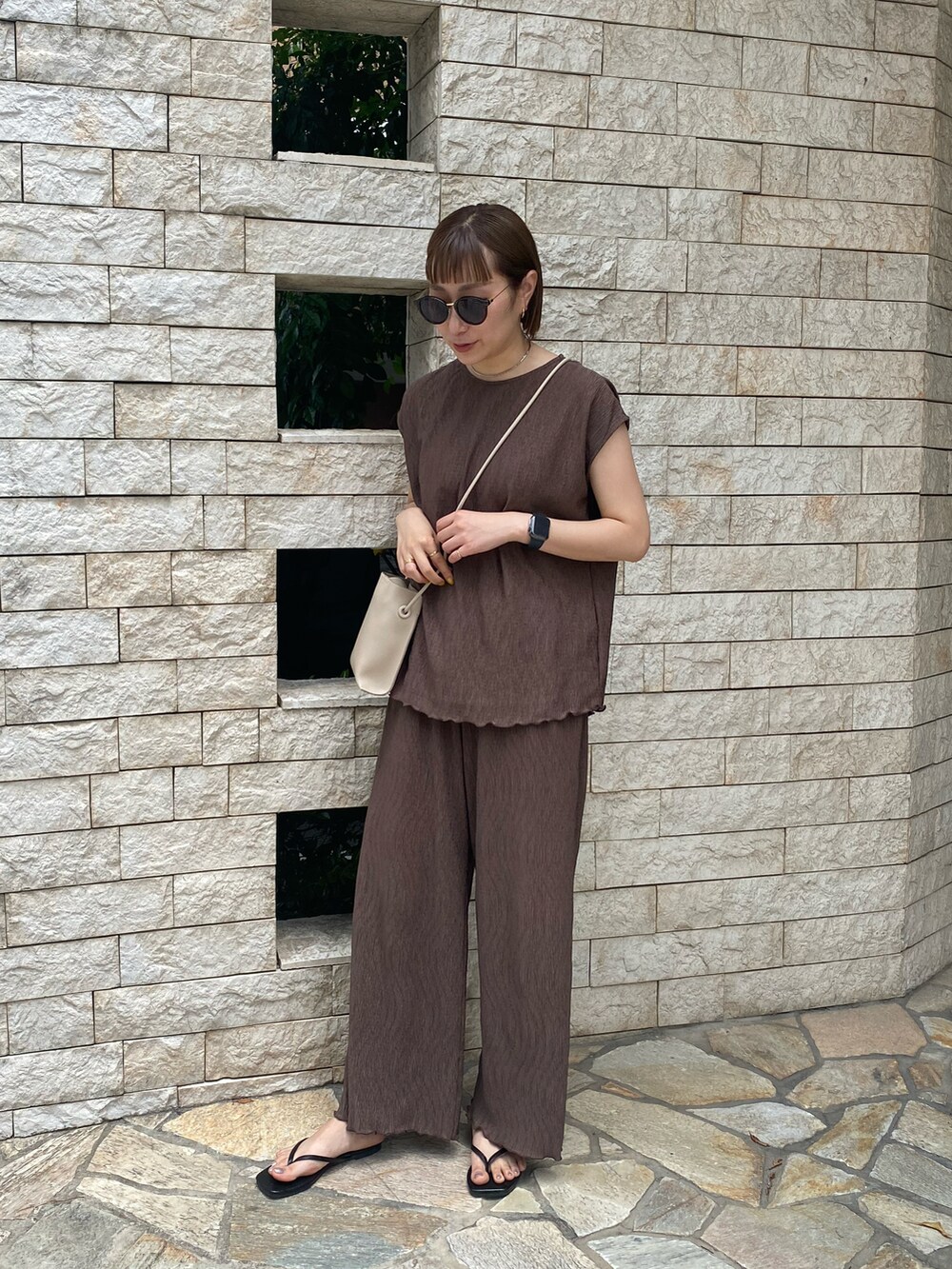 ブラウン系のセットアップ、ブラック系のサンダル、ホワイト系のショルダーバッグを着用したレディースの春コーディネートの2枚目の写真