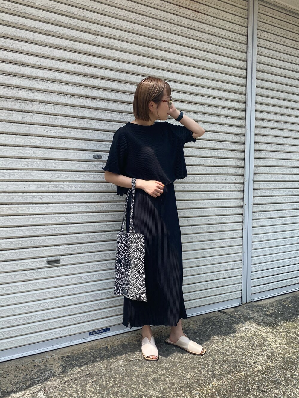 ブラック系のワンピース、ホワイト系のサンダルを着用したレディースの春コーディネートの2枚目の写真