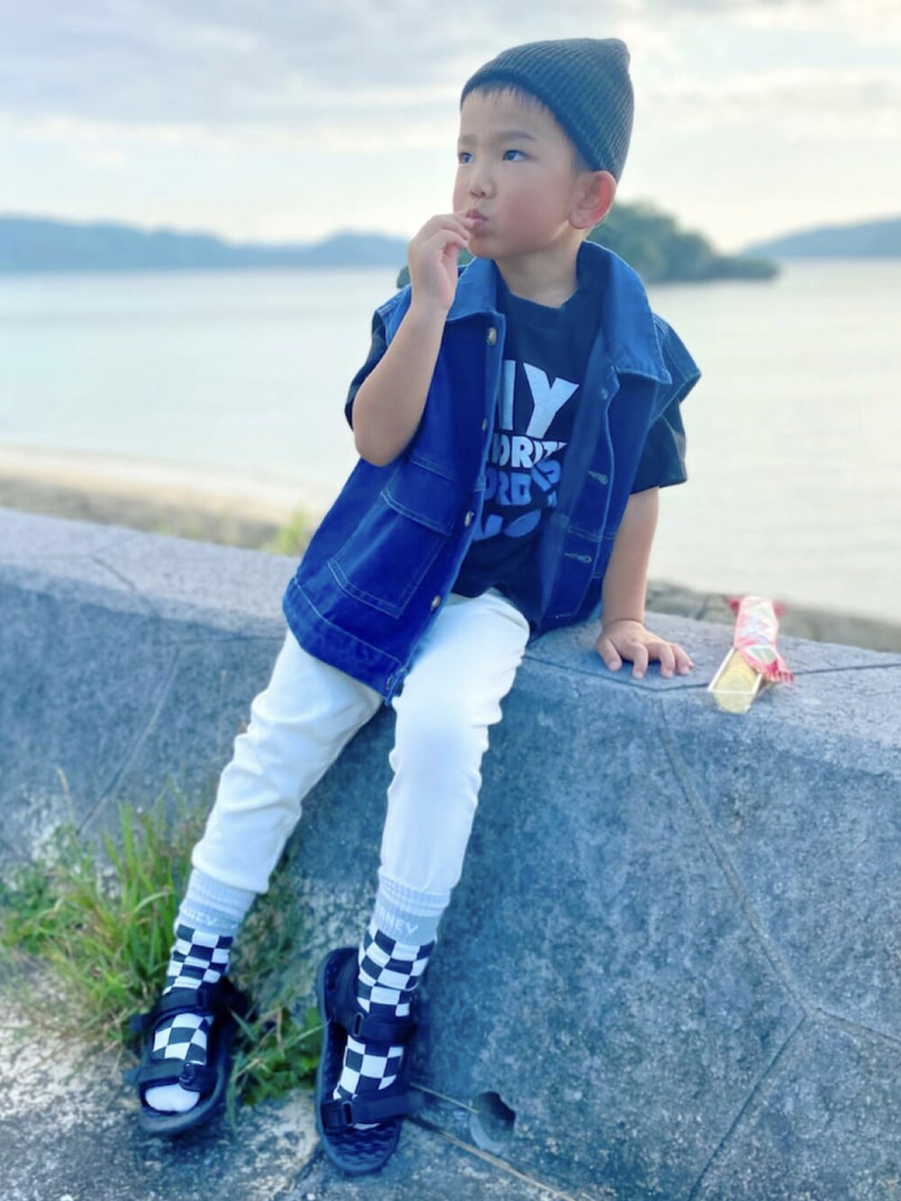 ブラック系のTシャツ/カットソー、ブルー系のベスト、ホワイト系のスカートを着用したレディースの春コーディネートの2枚目の写真