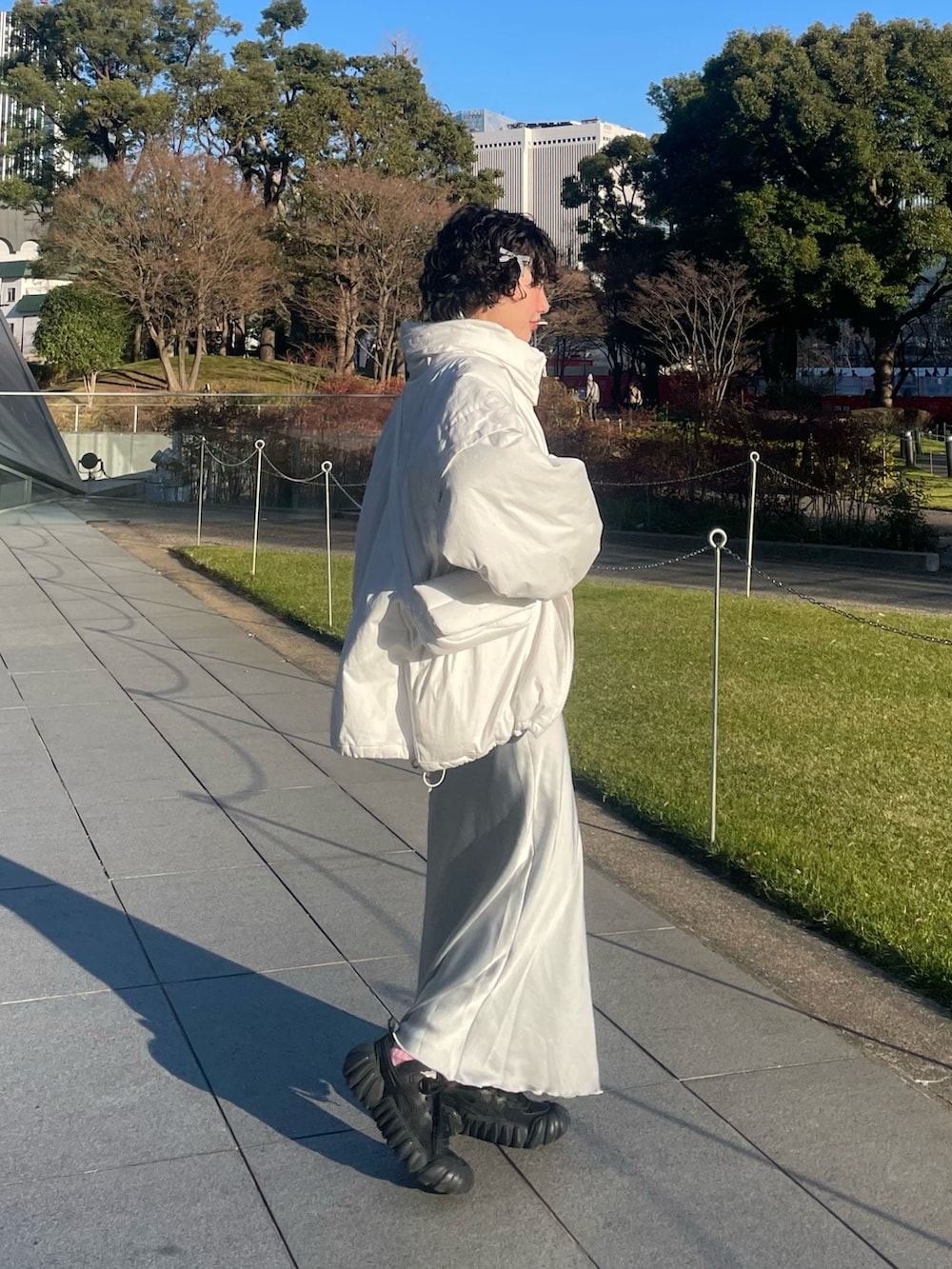 ベージュ系のスウェット、シルバー系のスカート、ブラック系のスニーカーを着用したレディースの冬コーディネートの2枚目の写真