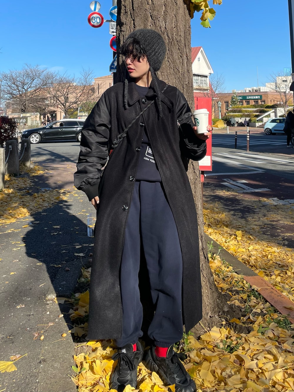 ブラック系のスニーカー、ブルー系のスウェットパンツ、ブラック系のその他アウターを着用したレディースの冬コーディネートの2枚目の写真