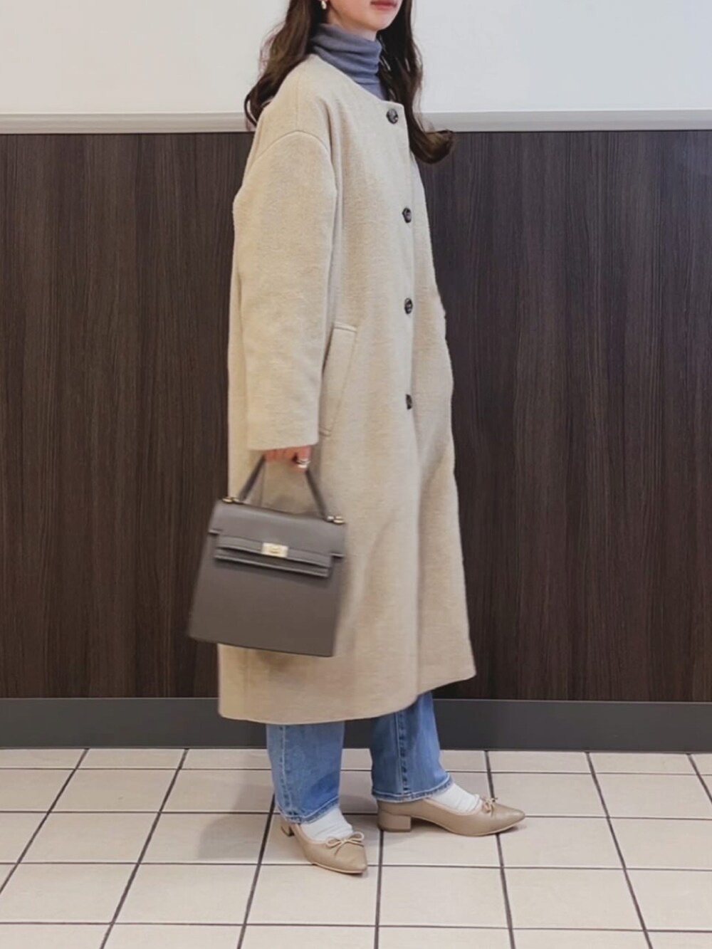 グレー系のバッグ、ブルー系のデニムパンツ、ベージュ系のパンプスを着用したレディースの冬コーディネートの3枚目の写真