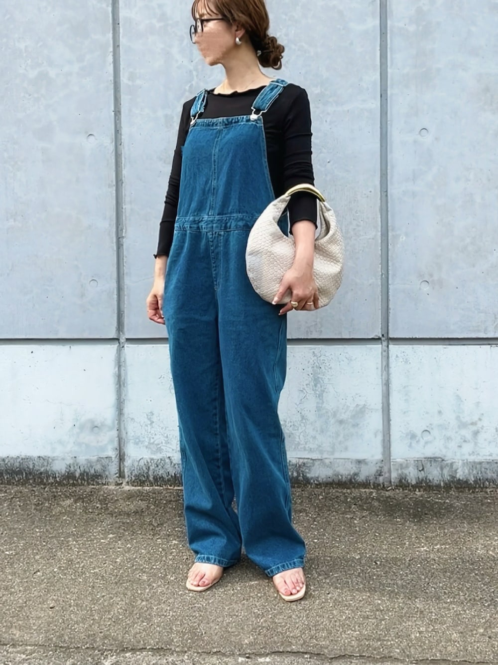ブルー系のサロペット/オーバーオール、ブラック系のTシャツ/カットソー、ベージュ系のサンダルを着用したレディースの春コーディネートの2枚目の写真