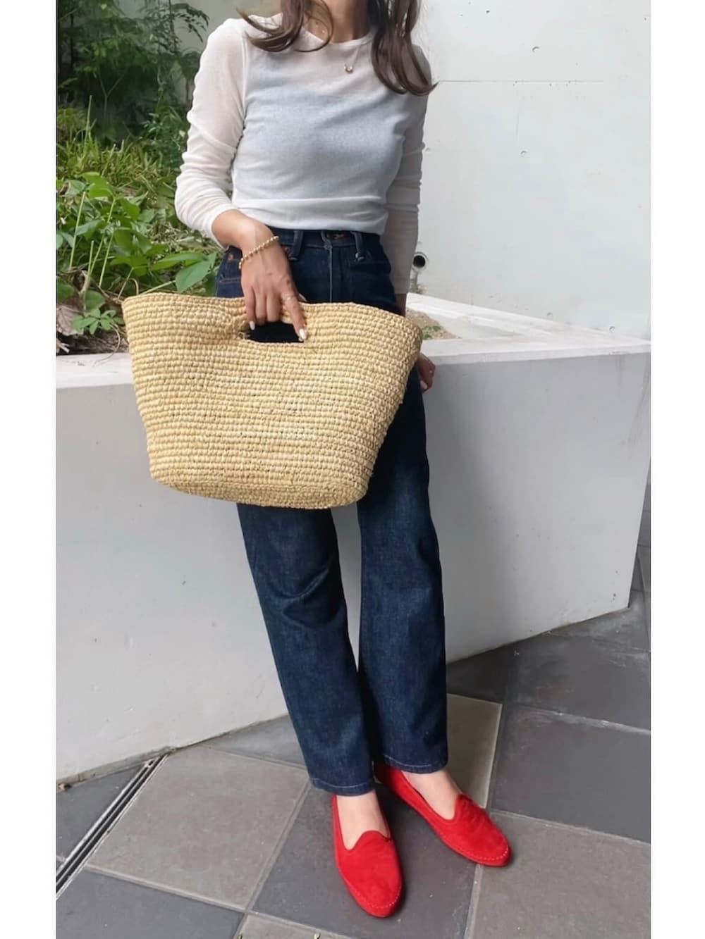 ブルー系のデニムパンツ、レッド系のモカシン/デッキシューズ、ベージュ系のかごバッグを着用したレディースの秋コーディネートの2枚目の写真