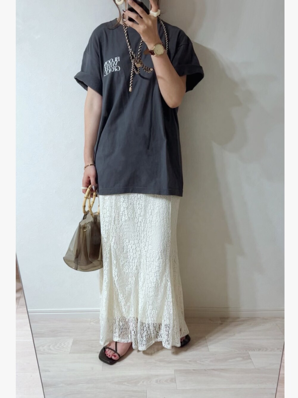 ブラック系のTシャツ/カットソー、ホワイト系のスカート、ブラック系のバッグを着用したレディースの夏コーディネートの2枚目の写真