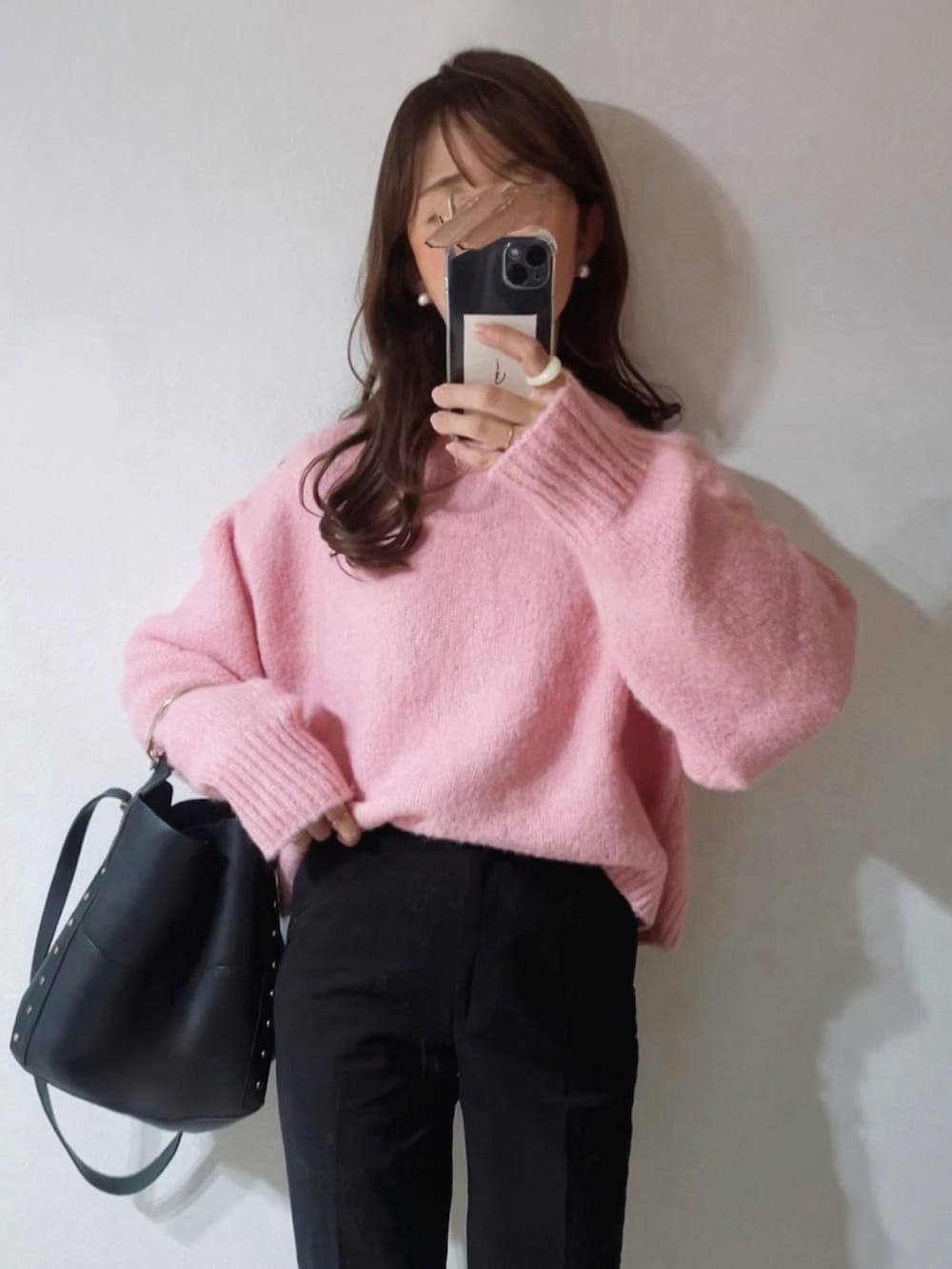 ピンク系のニット/セーター、ブラック系のバッグ、ブラック系のスニーカーを着用したレディースの冬コーディネートの2枚目の写真