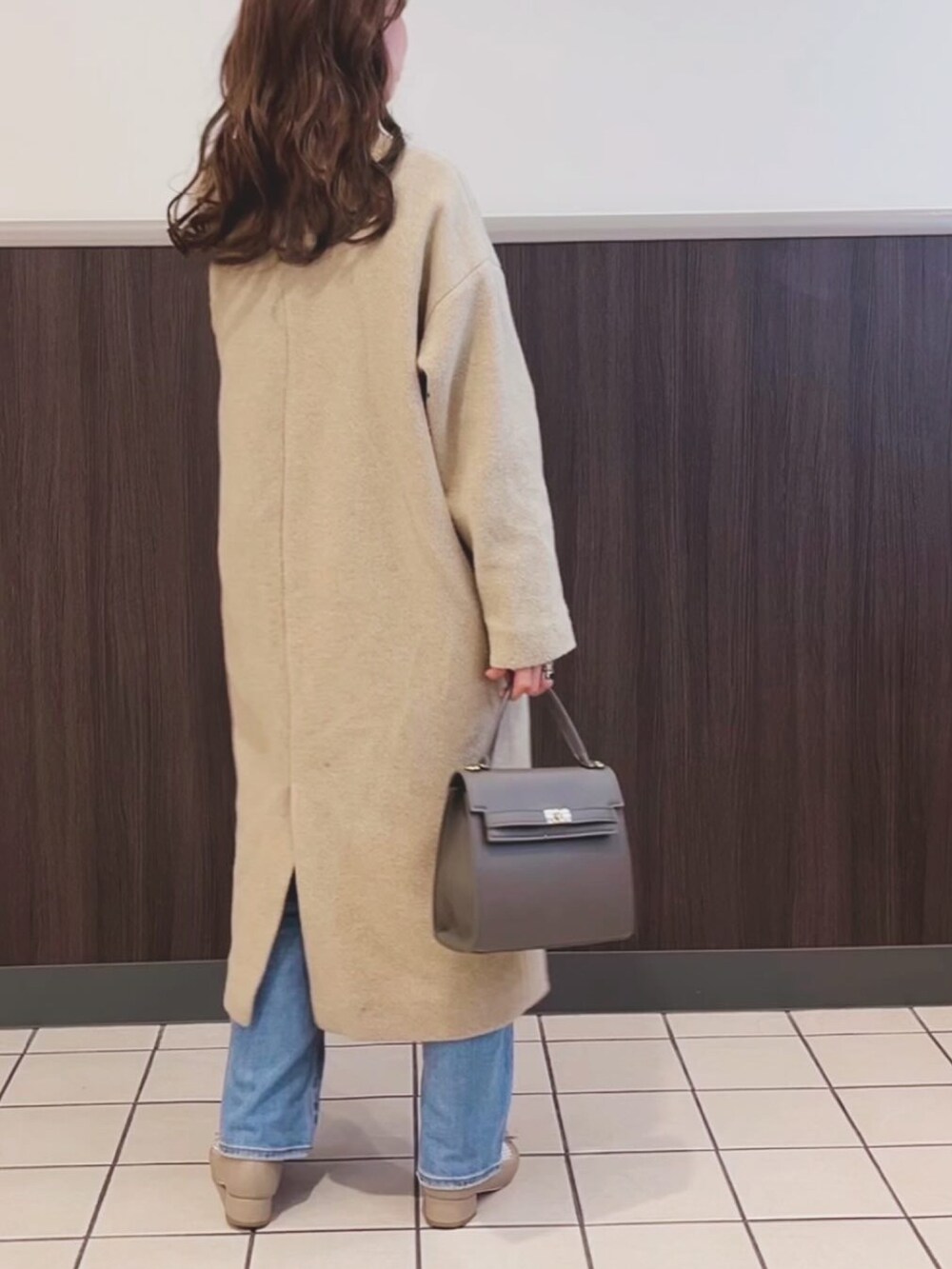 グレー系のバッグ、ブルー系のデニムパンツ、ベージュ系のパンプスを着用したレディースの冬コーディネートの2枚目の写真