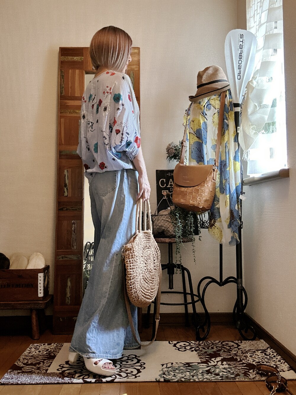 グレー系のTシャツ/カットソー、ベージュ系のかごバッグ、ブルー系のデニムパンツを着用したレディースの夏コーディネートの2枚目の写真