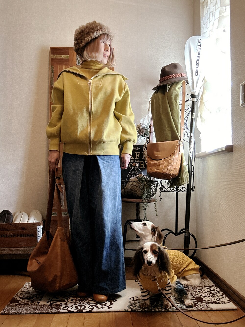 イエロー系のブルゾン、イエロー系のニット/セーター、ブルー系のデニムパンツを着用したレディースの冬コーディネートの2枚目の写真