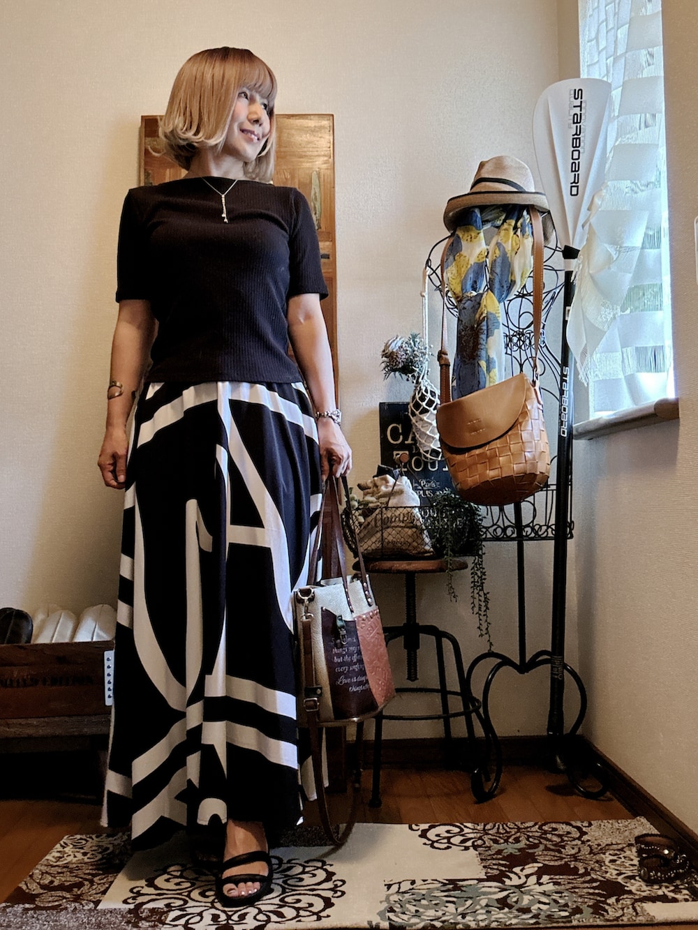 ブラック系のスカート、ブラウン系のショルダーバッグ、ブラック系のTシャツ/カットソーを着用したレディースの秋コーディネートの3枚目の写真