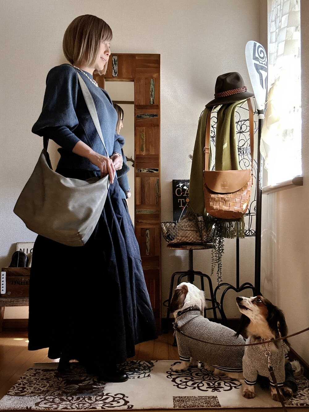 グレー系のショルダーバッグ、ブルー系のニット/セーター、ブラック系のスカートを着用したレディースの春コーディネートの2枚目の写真