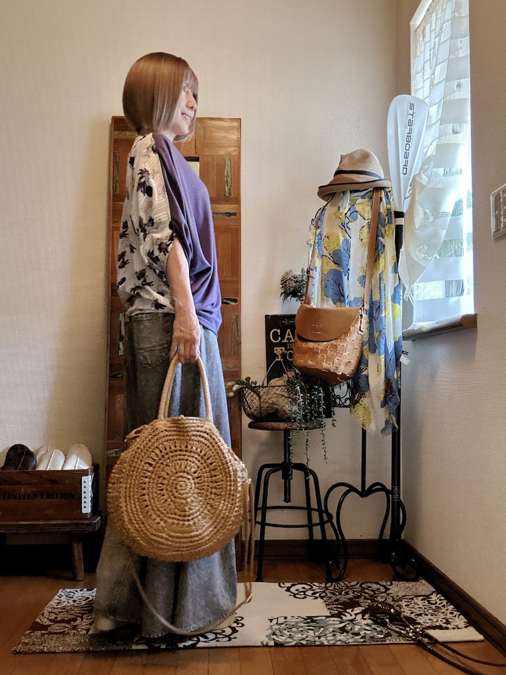 パープル系のTシャツ/カットソー、ブラック系のデニムパンツ、ベージュ系のかごバッグを着用したレディースの夏コーディネートの2枚目の写真