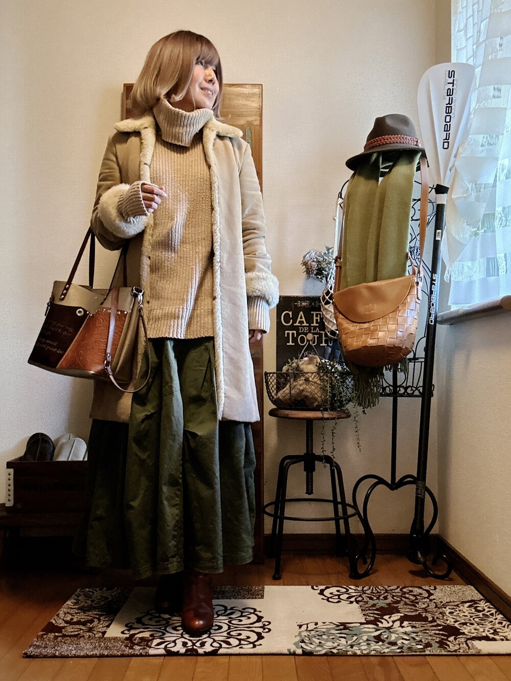 ブラウン系のショルダーバッグ、ベージュ系のムートンコート、ベージュ系のニット/セーターを着用したレディースの冬コーディネートの2枚目の写真