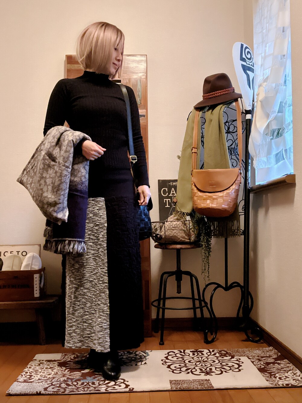 ブラック系のニット/セーター、ブラック系のスカート、ブラック系のブーツを着用したレディースの冬コーディネートの2枚目の写真