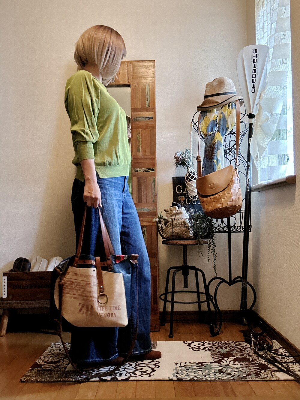 グリーン系のニット/セーター、ブルー系のデニムパンツ、ブルー系のトートバッグを着用したレディースの秋コーディネートの2枚目の写真