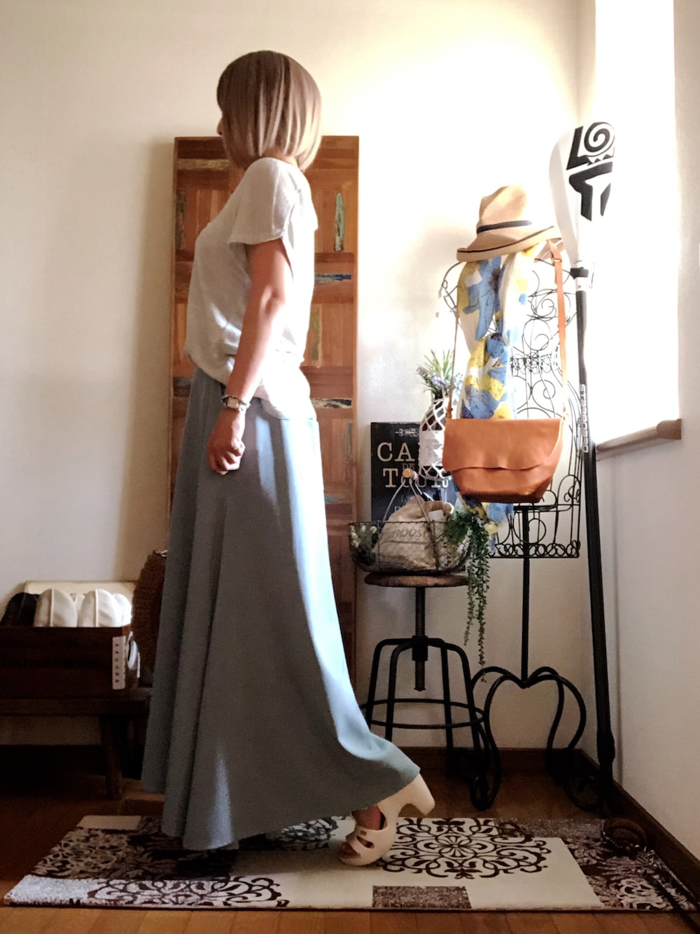 シルバー系のTシャツ/カットソー、ベージュ系のかごバッグ、グリーン系のスカートを着用したレディースの夏コーディネートの3枚目の写真