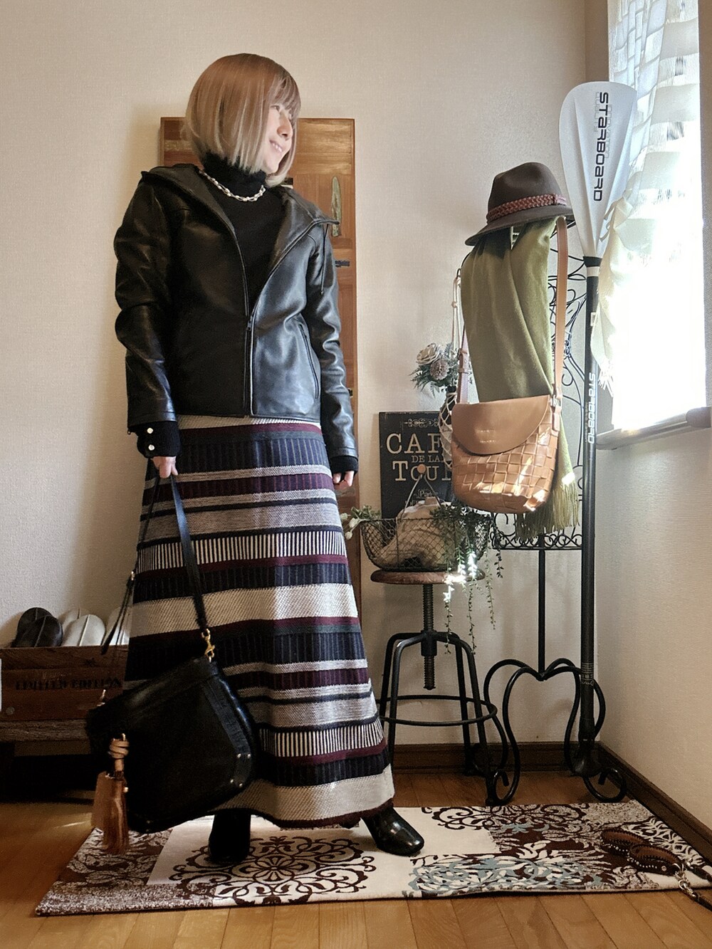 グリーン系のスカート、ブラック系のライダースジャケット、ブラック系のニット/セーターを着用したレディースの春コーディネートの2枚目の写真