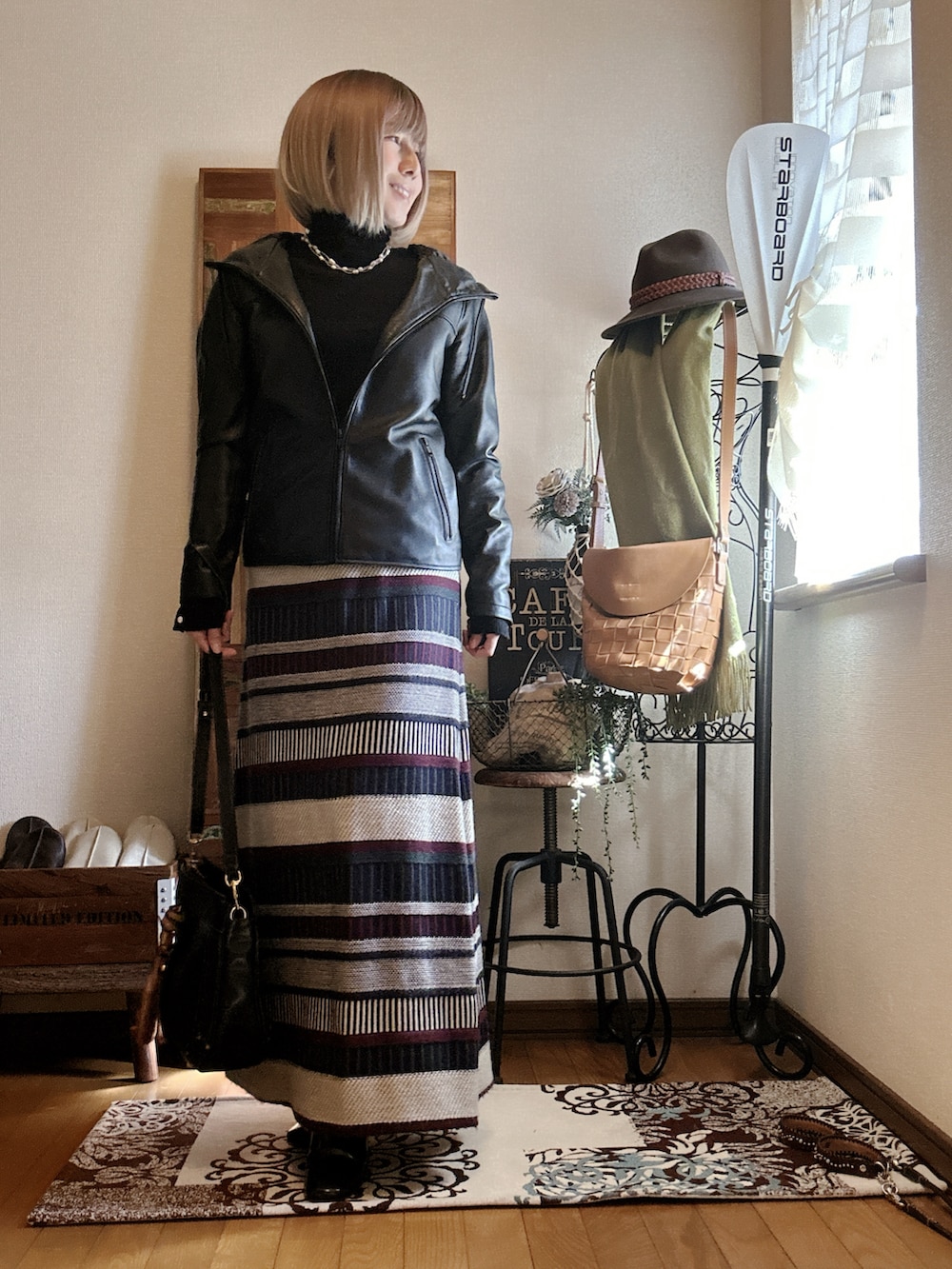 グリーン系のスカート、ブラック系のライダースジャケット、ブラック系のニット/セーターを着用したレディースの春コーディネートの3枚目の写真