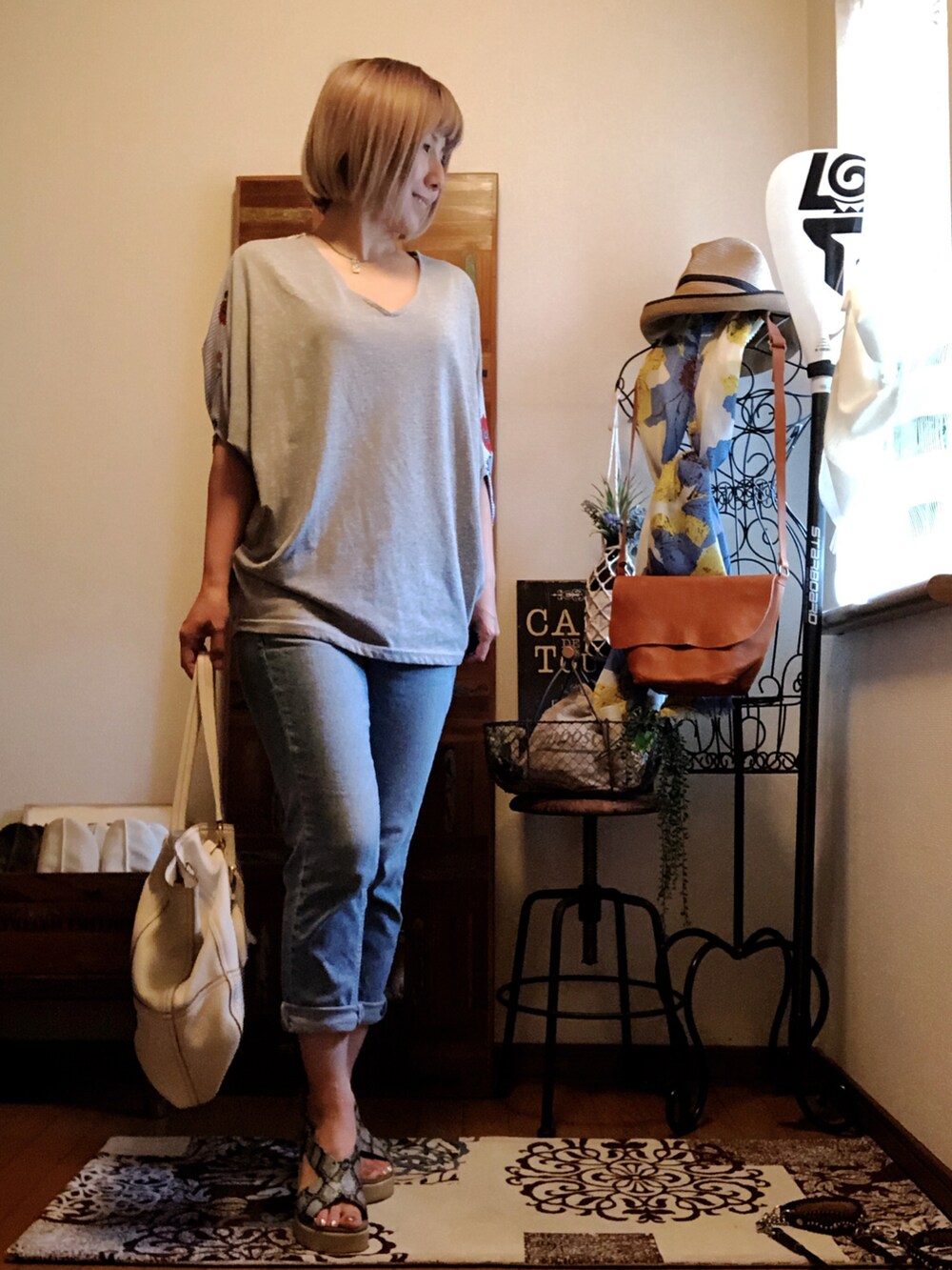 ホワイト系のバッグ、グレー系のTシャツ/カットソー、ブルー系のデニムパンツを着用したレディースの夏コーディネートの2枚目の写真