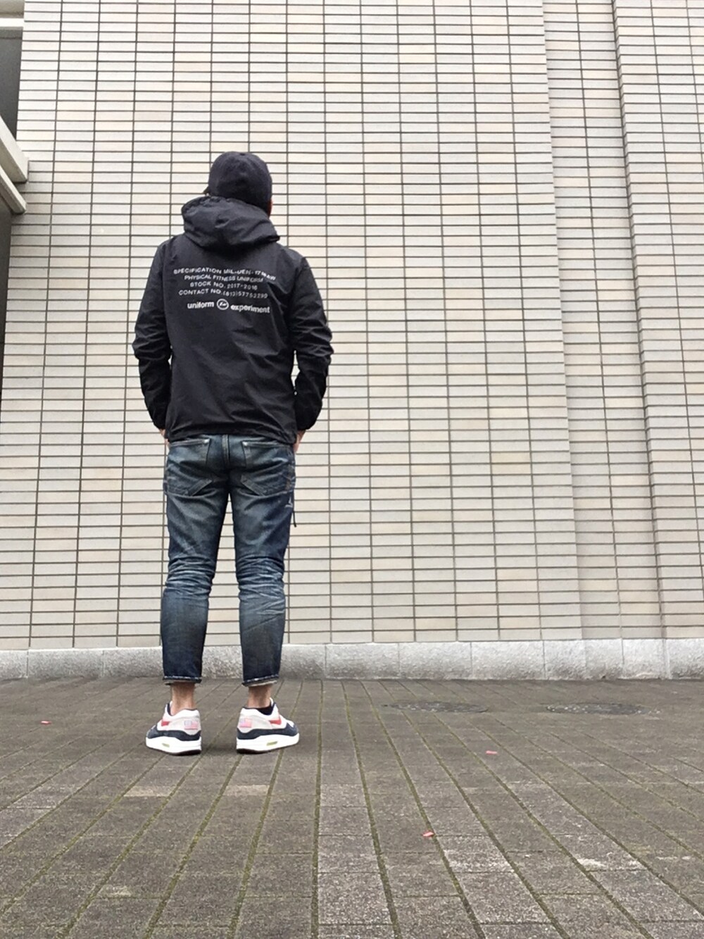ブラック系のナイロンジャケット、ブルー系のパンツ、ブルー系のスニーカーを着用したメンズの冬コーディネートの2枚目の写真