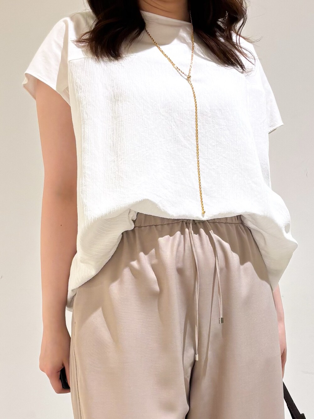 ホワイト系のTシャツ/カットソー、ベージュ系のその他パンツ、ブラック系のサンダルを着用したレディースの夏コーディネートの7枚目の写真