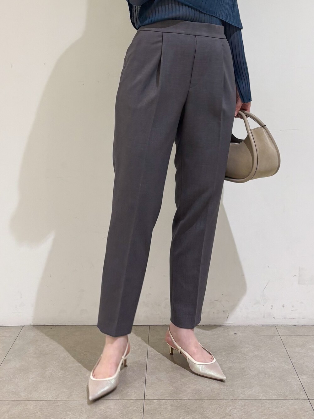 ブルー系のニット/セーター、グレー系のスラックスを着用したレディースの秋コーディネートの9枚目の写真