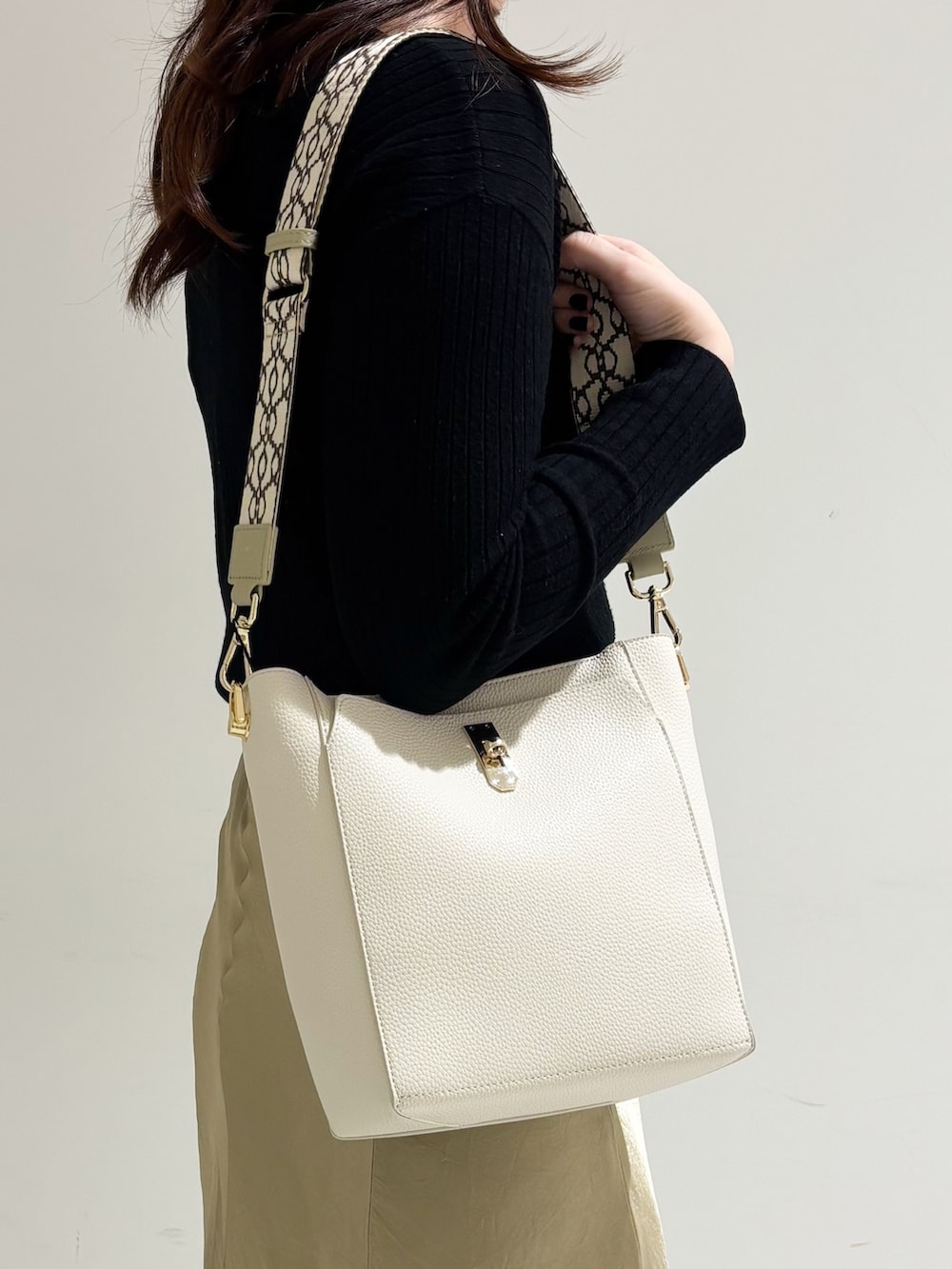 ベージュ系のショルダーバッグ、ホワイト系のトートバッグ、ブラック系のパンプスを着用したレディースの冬コーディネートの5枚目の写真