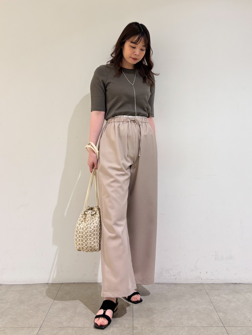 ベージュ系のその他パンツ、ホワイト系のショルダーバッグ、ブラック系のサンダルを着用したレディースの夏コーディネートの4枚目の写真