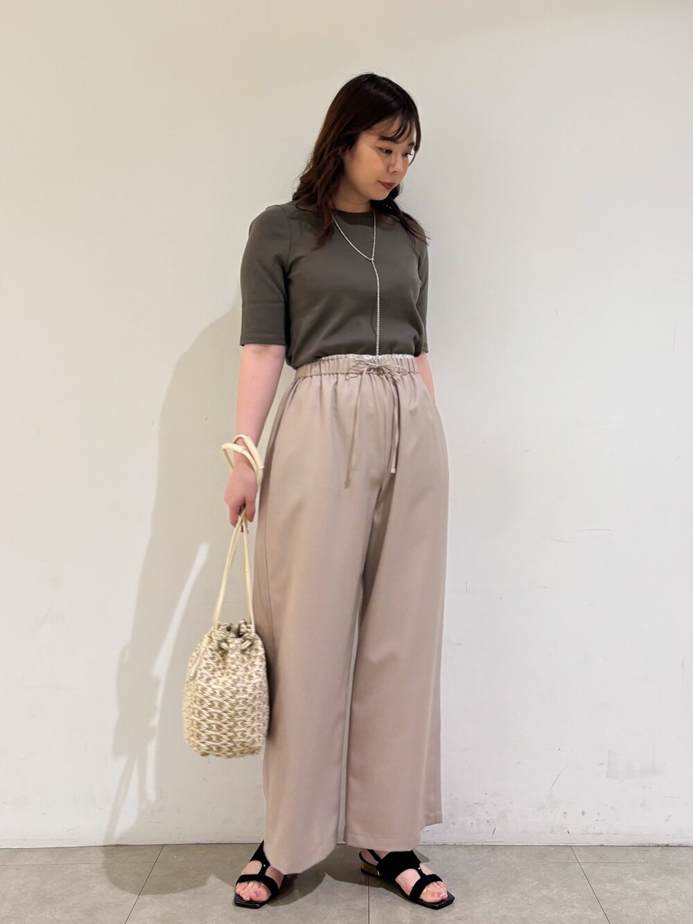 ベージュ系のその他パンツ、ホワイト系のショルダーバッグ、ブラック系のサンダルを着用したレディースの夏コーディネートの2枚目の写真