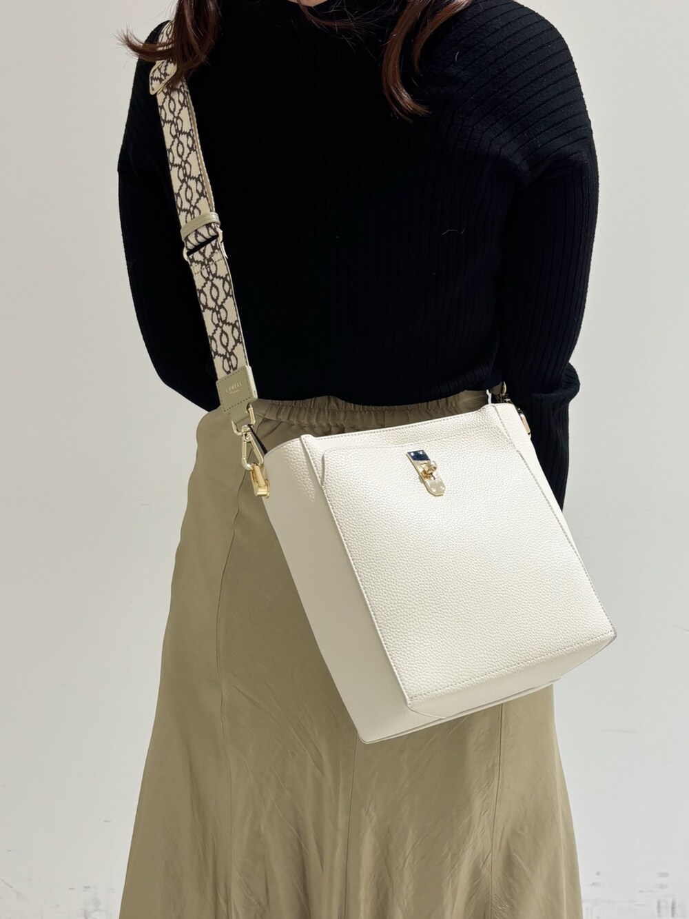 ベージュ系のショルダーバッグ、ホワイト系のトートバッグ、ブラック系のパンプスを着用したレディースの冬コーディネートの6枚目の写真