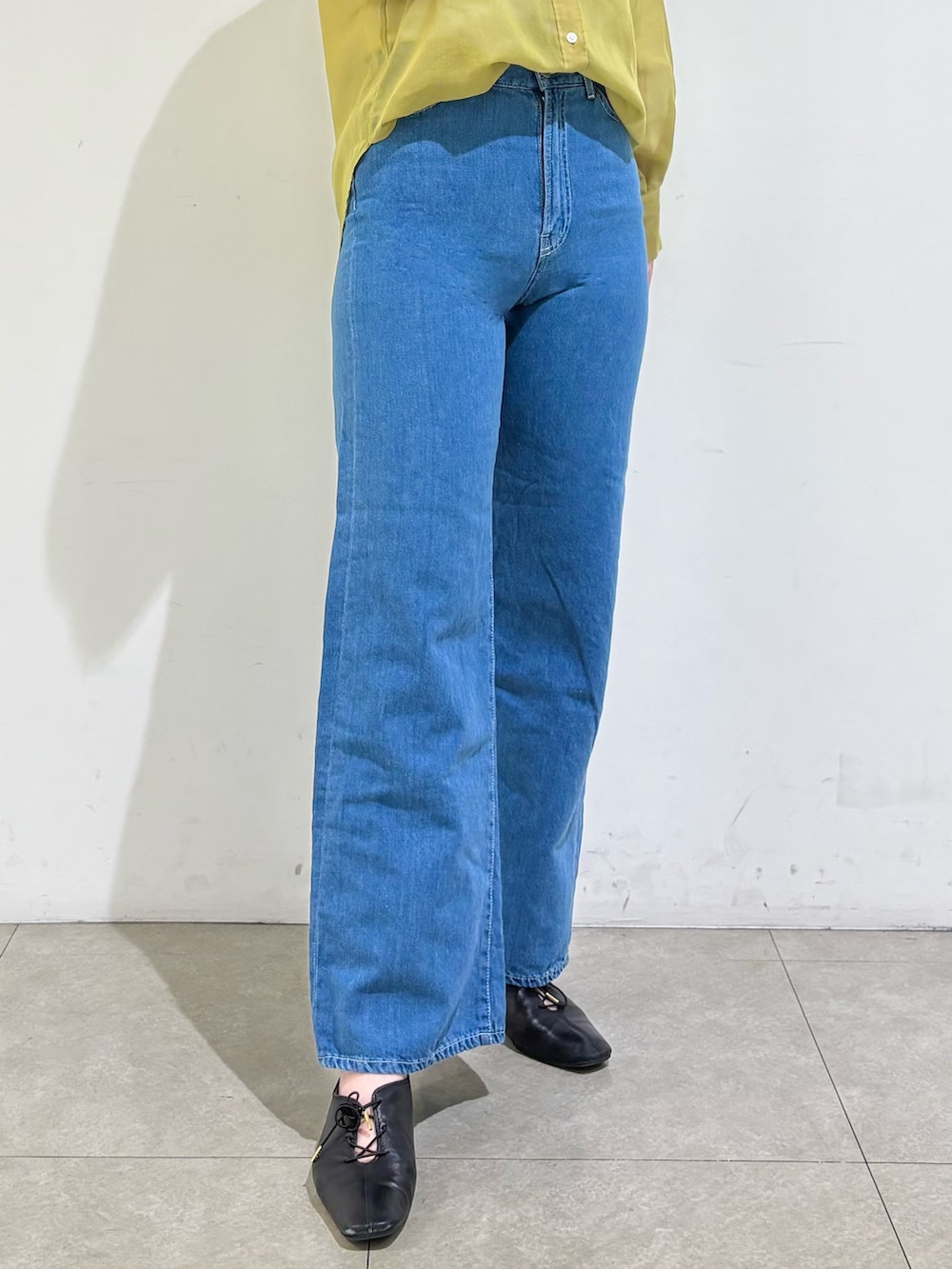 グレー系のタンクトップ、イエロー系のシャツ/ブラウス、ブルー系のデニムパンツを着用したレディースの春コーディネートの6枚目の写真