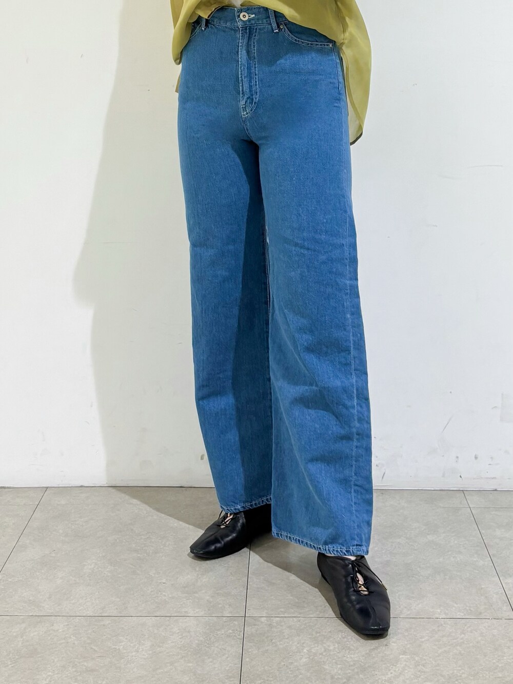 グレー系のタンクトップ、イエロー系のシャツ/ブラウス、ブルー系のデニムパンツを着用したレディースの春コーディネートの7枚目の写真