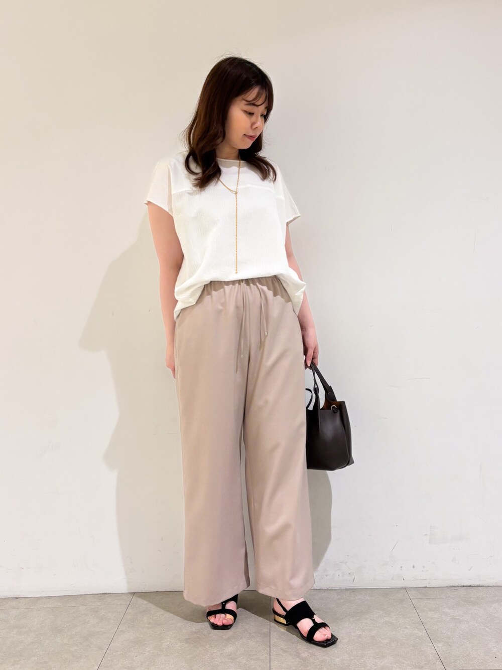 ホワイト系のTシャツ/カットソー、ベージュ系のその他パンツ、ブラック系のサンダルを着用したレディースの夏コーディネートの4枚目の写真