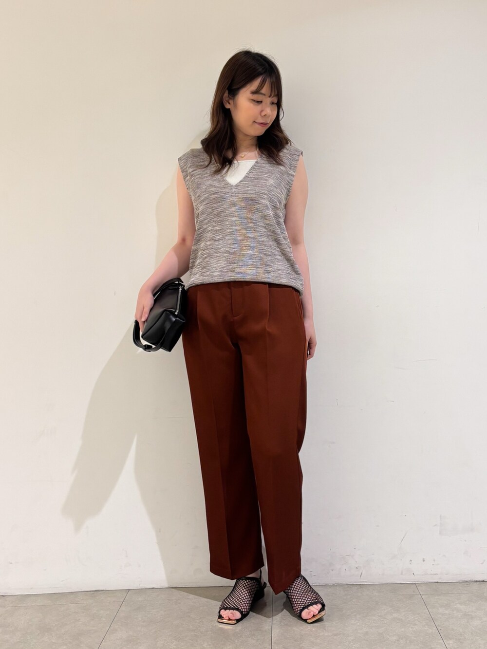 ピンク系のベスト、ブラウン系のその他パンツ、ブラック系のサンダルを着用したレディースの秋コーディネートの2枚目の写真