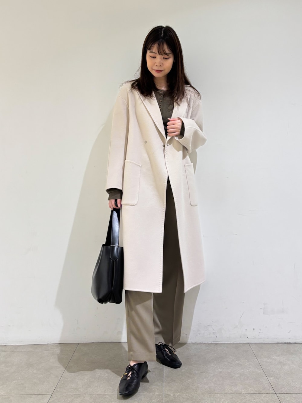 ベージュ系のチェスターコート、ブラウン系のニット/セーター、グリーン系のその他パンツを着用したレディースの秋コーディネートの4枚目の写真