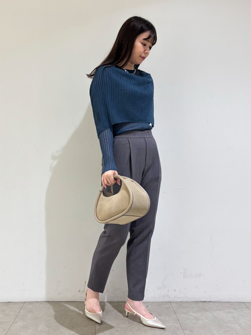 ブルー系のニット/セーター、グレー系のスラックスを着用したレディースの秋コーディネートの4枚目の写真