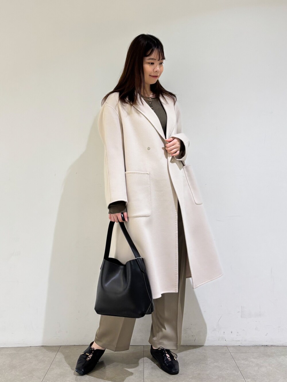 ベージュ系のチェスターコート、ブラウン系のニット/セーター、グリーン系のその他パンツを着用したレディースの秋コーディネートの3枚目の写真