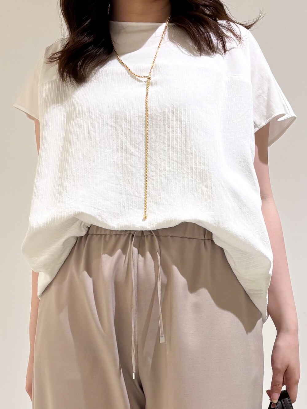 ホワイト系のTシャツ/カットソー、ベージュ系のその他パンツ、ブラック系のサンダルを着用したレディースの夏コーディネートの6枚目の写真