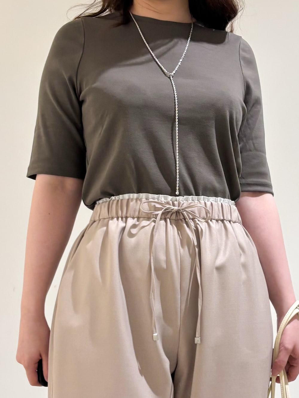 ベージュ系のその他パンツ、ホワイト系のショルダーバッグ、ブラック系のサンダルを着用したレディースの夏コーディネートの6枚目の写真