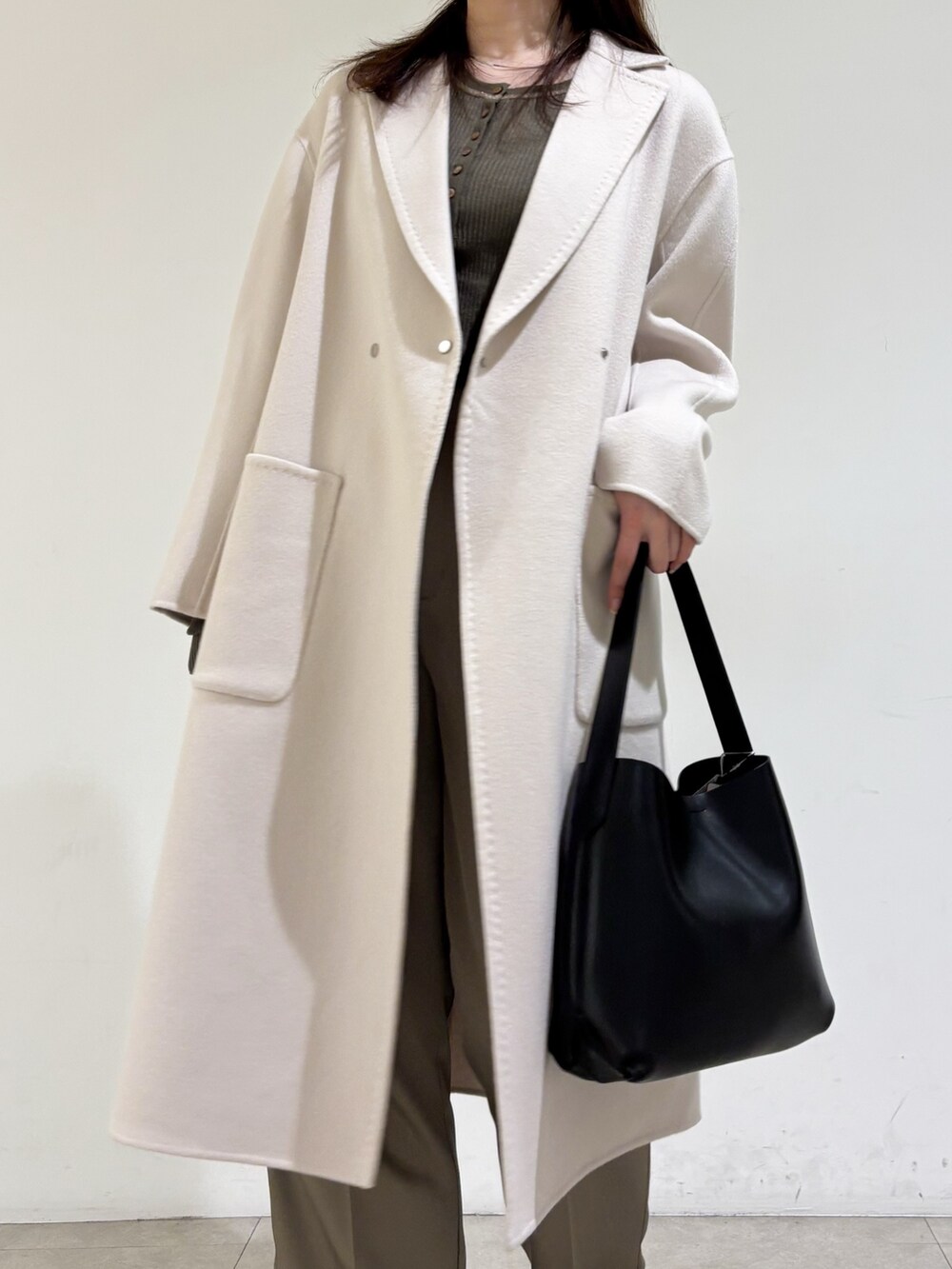 ベージュ系のチェスターコート、ブラウン系のニット/セーター、グリーン系のその他パンツを着用したレディースの秋コーディネートの6枚目の写真